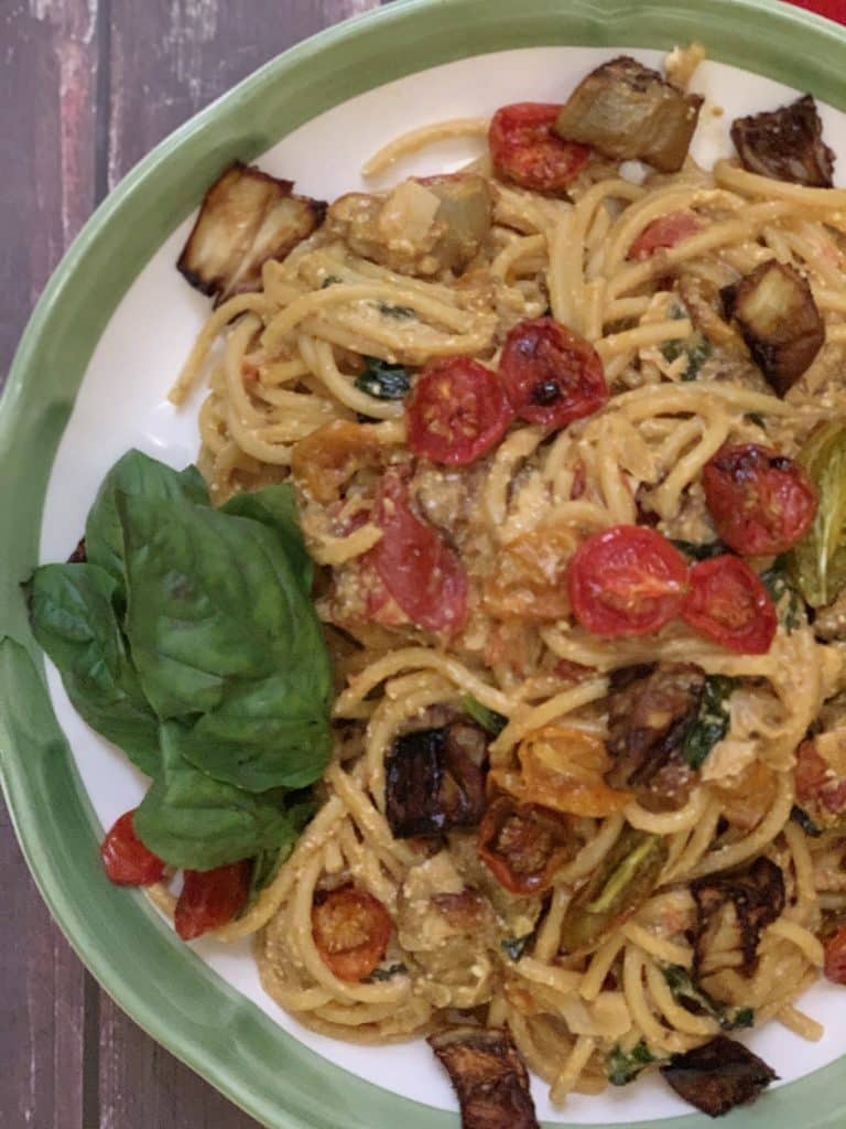 Bucatini with Ricotta, Slow-Roasted Eggplant and Tomatoes with basil garnish on serving platter.