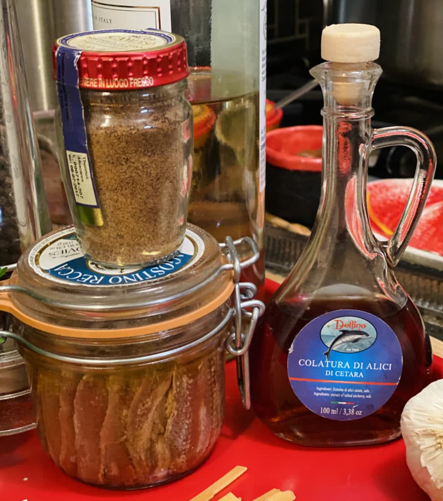 Bottle of colatura, jar of anchovies, jar of grated bottarga.