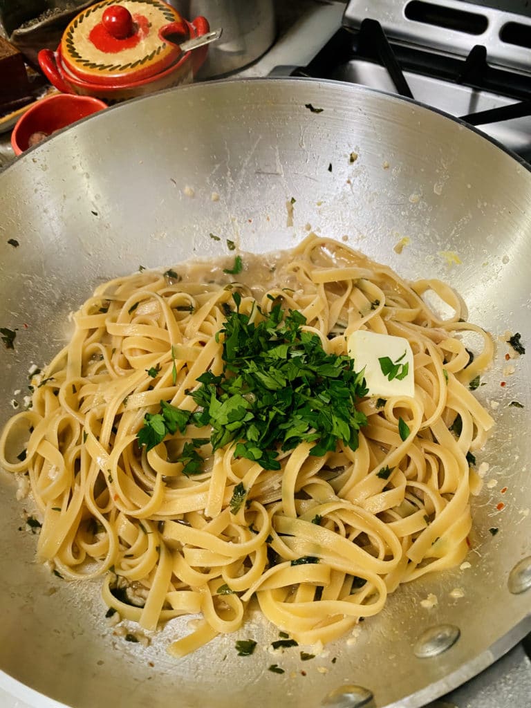 Cooked pasta in pan with butter and parsley.