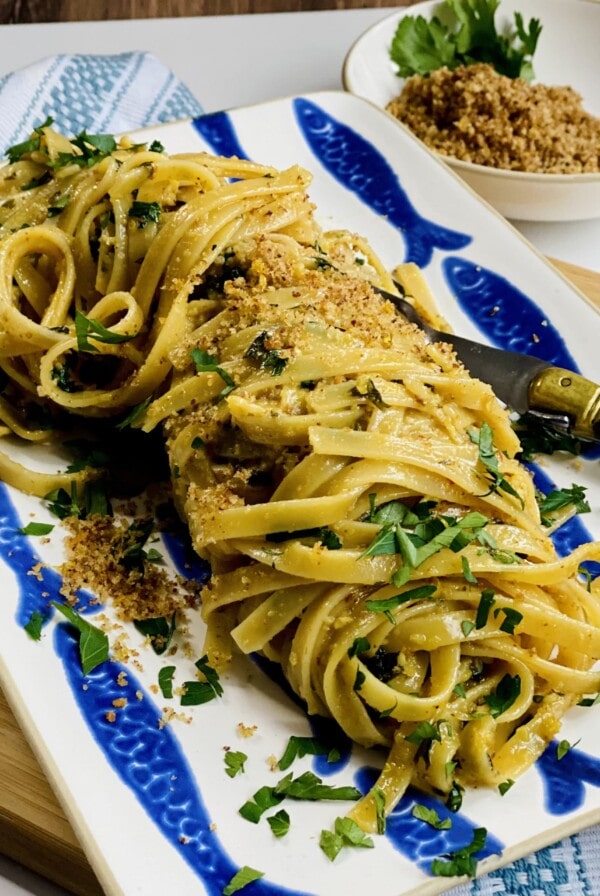 Finished, styled pasta on platter with breadcrumbs in background.