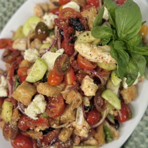 Panzanella Toscana finished and displayed on platter with an overhead view and large garnish leaf of basil.