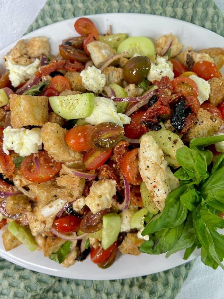 Panzanella Toscana finished and displayed on platter with an overhead view and large garnish leaf of basil.
