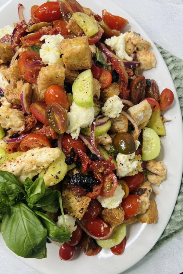 Panzanella Toscana finished and displayed on platter with an overhead view and large garnish leaf of basil.