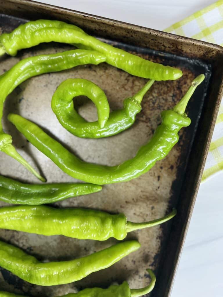 Corner view of long hot peppers in a single layer on a sheet pan.