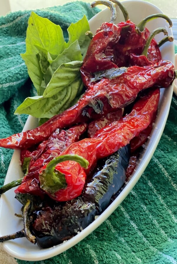Finished Fried Italian Sweet Peppers with fresh basil on oval white platter.