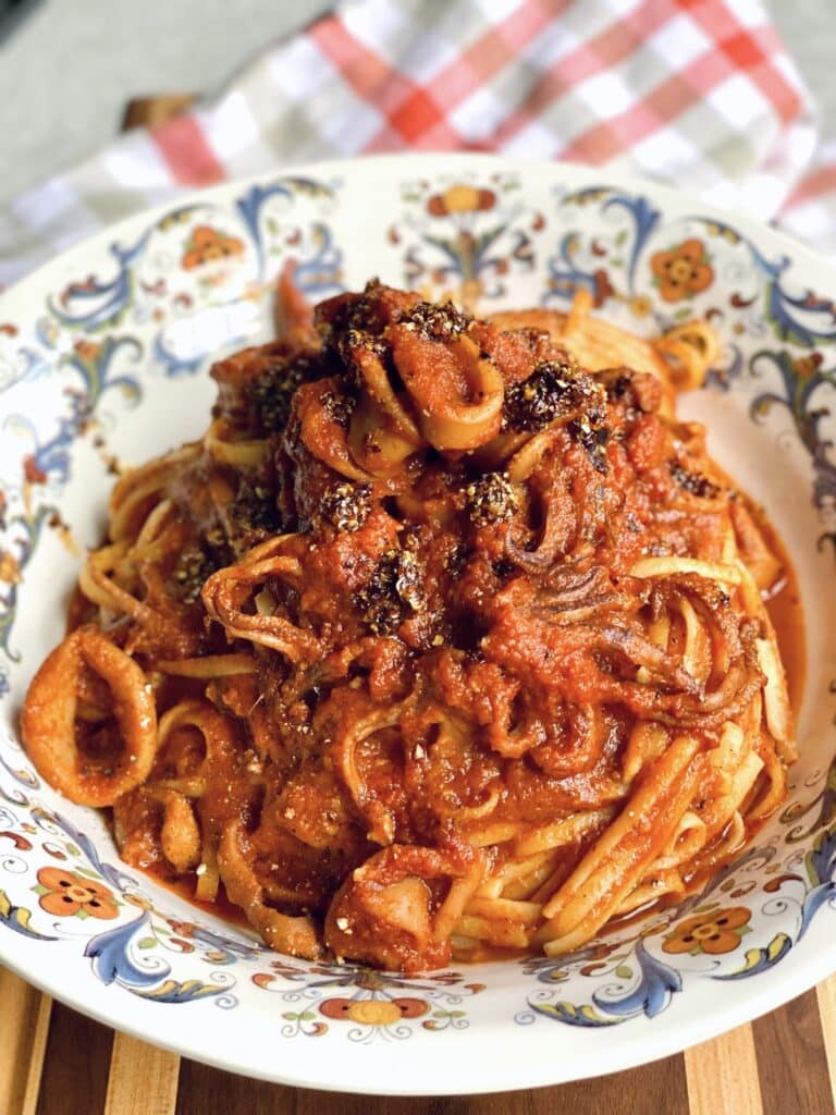 Italian Chili Oil on a bowl of pasta with red calamari sauce in a decorative bowl.