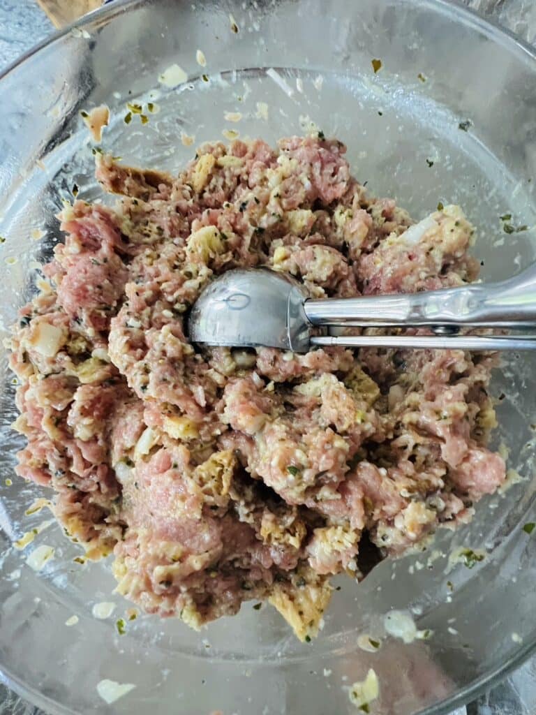 Portion scoop in bowl with turkey meatball mixture.