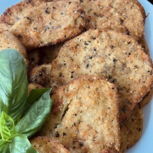 Eggplant Milanese Cutlets with basil garnish on white platter.