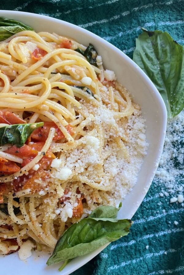 Overhead photo of pasta with quick grape tomato sauce styled in bowl with fresh basil garnish.