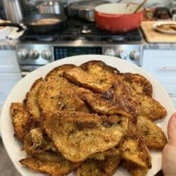 Eggplant Milanese on white dish with stove in background.