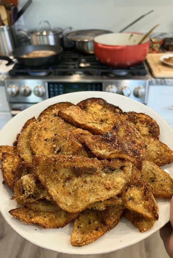 Eggplant Milanese on white dish with stove in background.