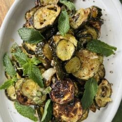 Zucchini alla scapece styled on white platter with fresh mint.