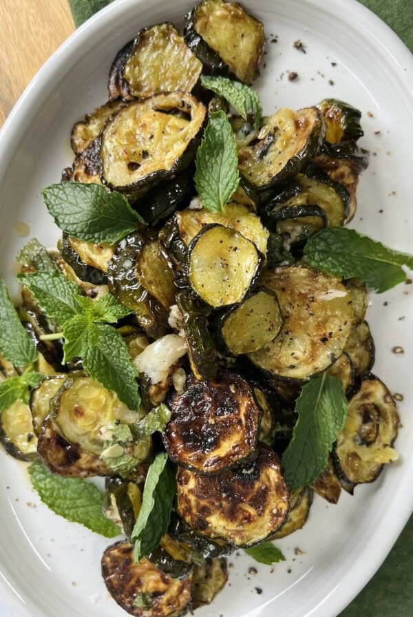 Zucchini alla scapece styled on white platter with fresh mint.