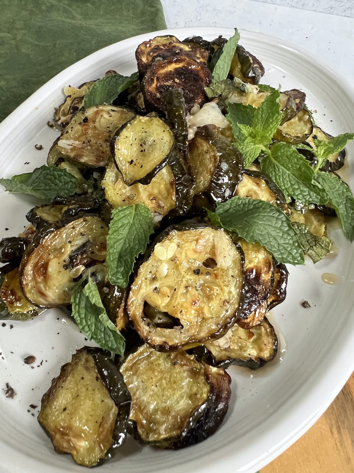 Zucchini alla scapece styled on white platter with fresh mint.