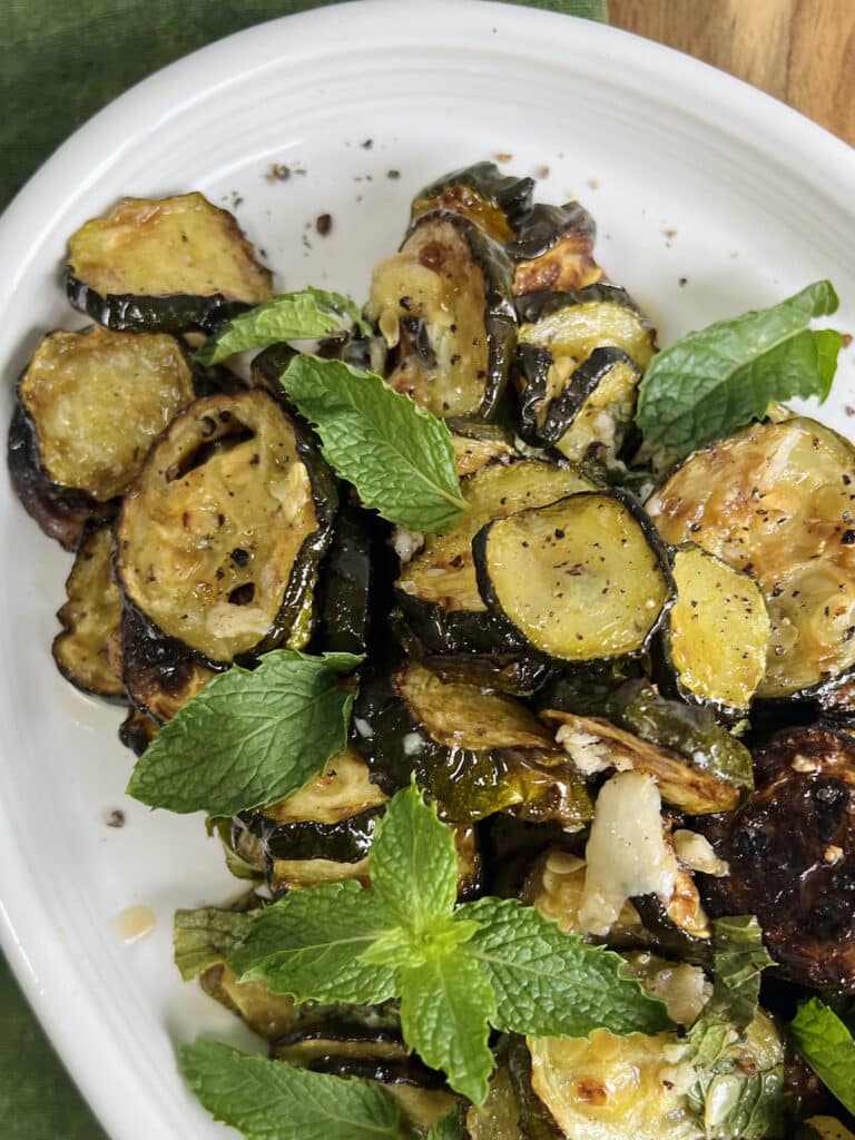 Zucchini alla scapece styled on white platter with fresh mint.