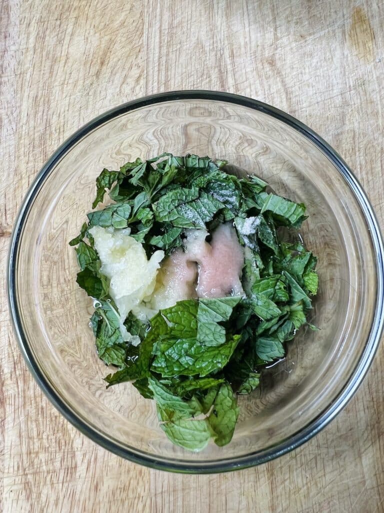 Mint, salt and garlic marinating in vinegar in small bowl.