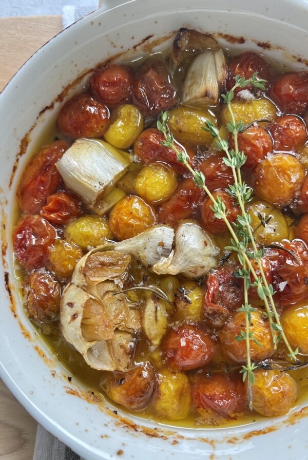 Finished Confit Cherry Tomatoes and Garlic in round white baking dish.