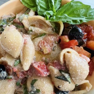 Finished and styled pasta all checca in pasta bowl with basil garnish.