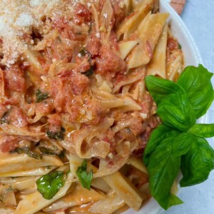 Homemade vodka sauce with fresh tomatoes styled in bowl with fresh basil.