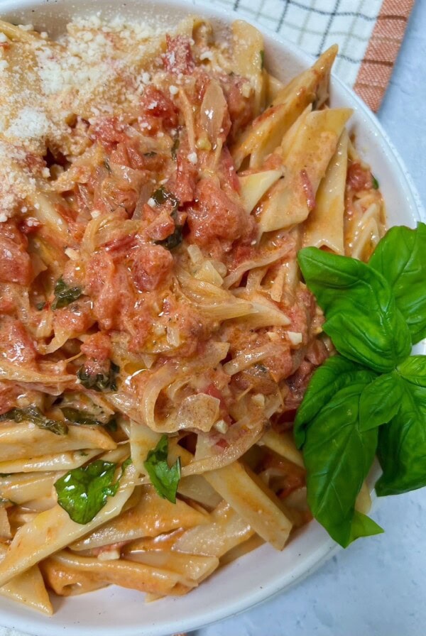 Homemade vodka sauce with fresh tomatoes styled in bowl with fresh basil.