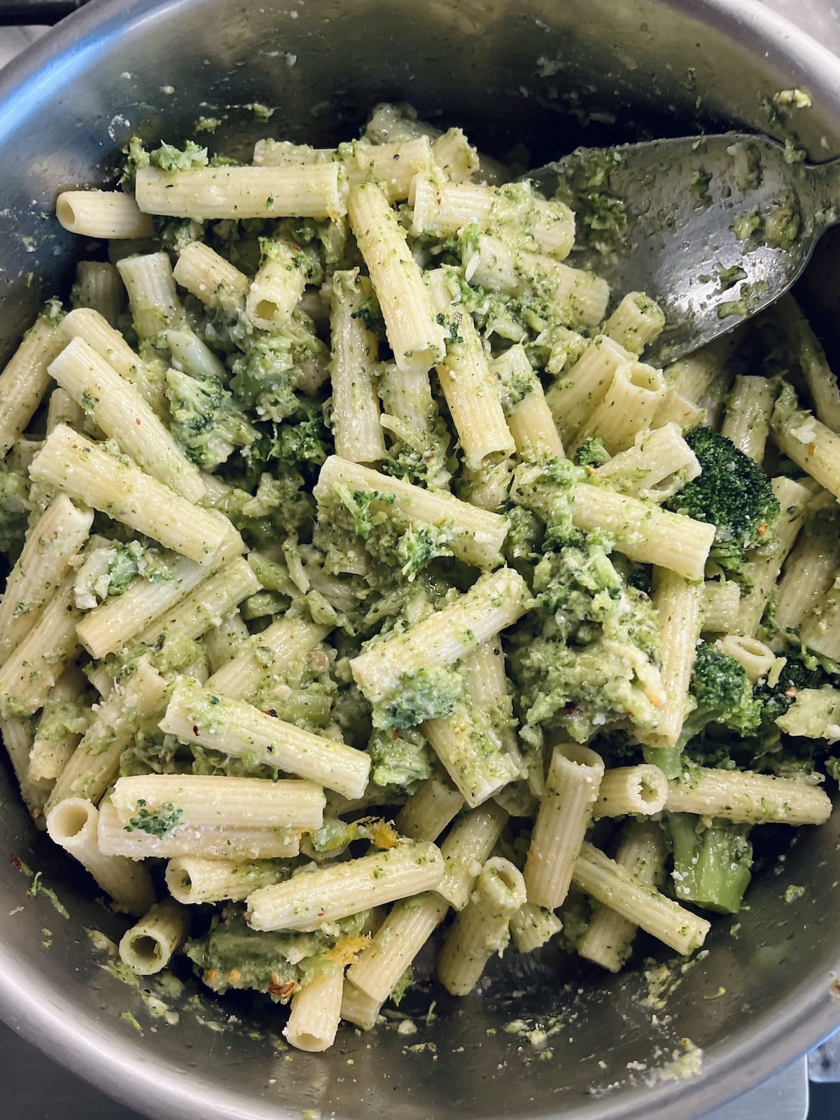 Italian Broccoli Pasta in pan with stainless steel spoon.