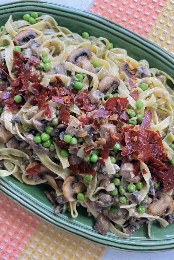 Finished styled photo of Paglia e Fieno pasta on green oval platter.