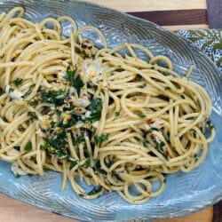 Finished Spaghetti aglio olio peperoncino on blue platter.