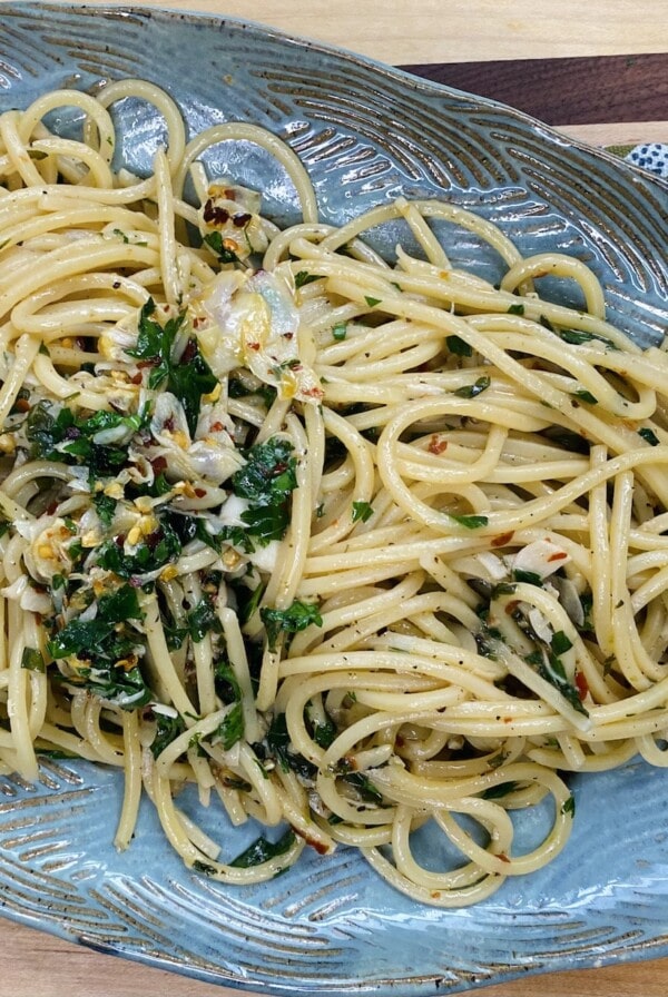 Finished Spaghetti aglio olio peperoncino on blue platter.