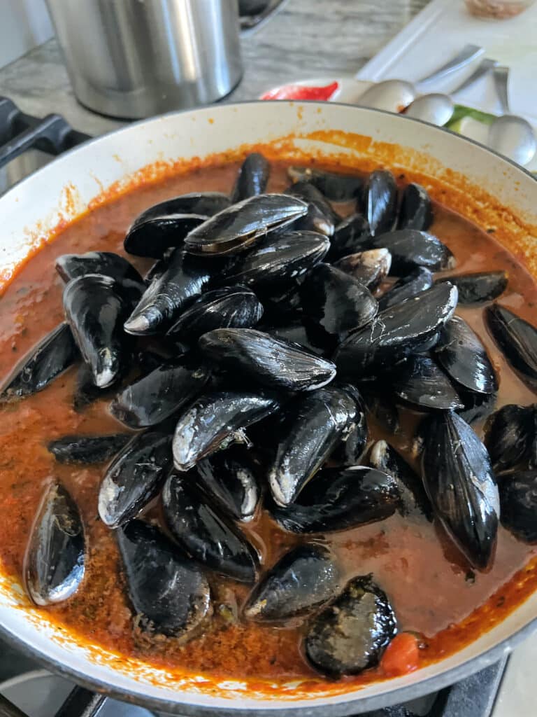 Mussels just added to pan of tomato sauce for Italian mussels in red sauce.