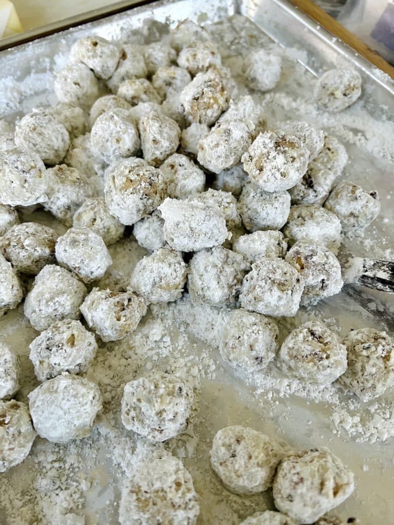 Snowball cookies on sheet pan just tossed in powdered sugar.
