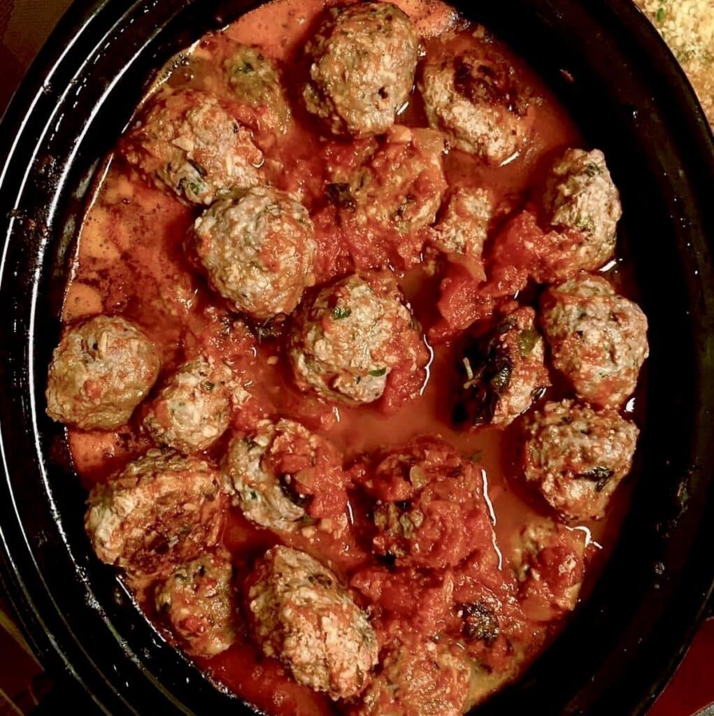 A slow cooker filled with meatballs no bread crumbs and tomato sauce-ready for a big crowd!