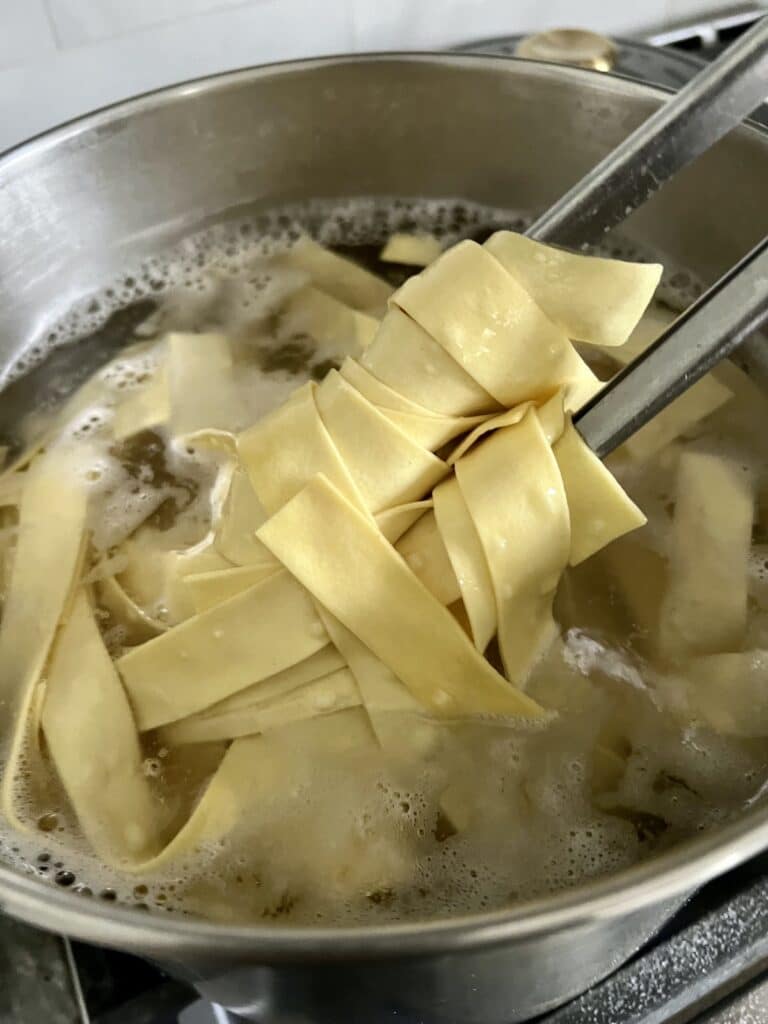 Pappardelle pasta cooking in salted boiling water.