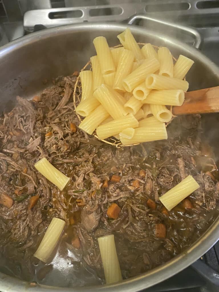 Adding cooked pasta to brisket ragu.