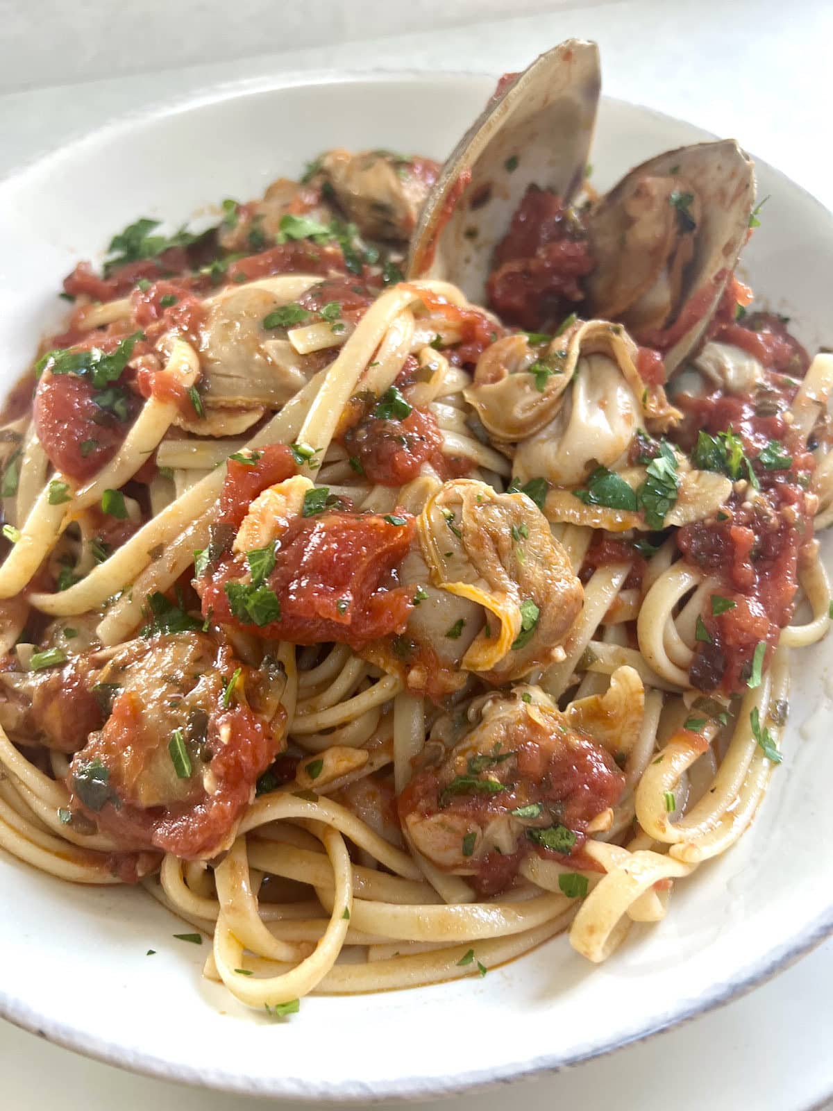 Authentic Italian Red Clam Sauce with Linguine styled in white bowl.