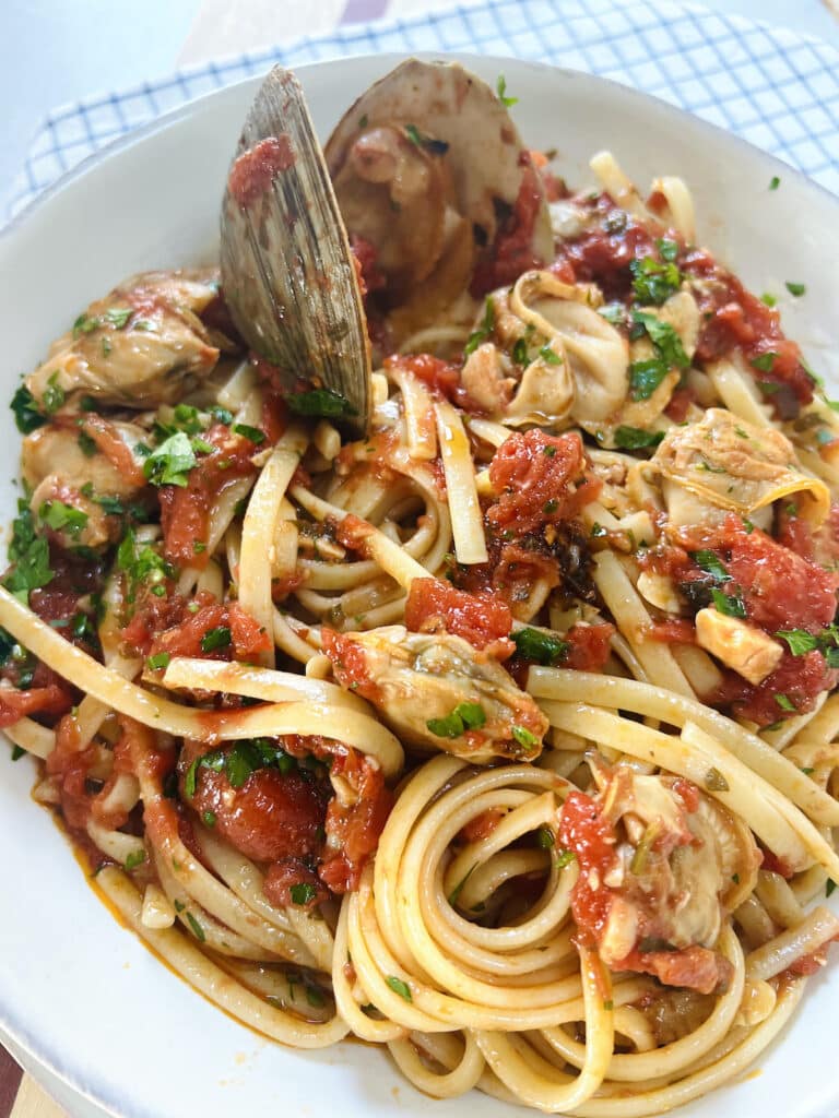 Authentic Italian Red Clam Sauce with Linguine styled in white bowl.