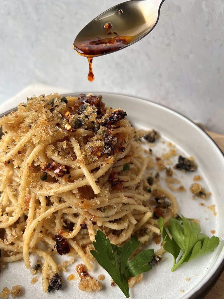 Drizzling spicy pepper oil over spaghetti ca muddica aka st joseph's spaghetti with breadcrumbs and anchovies.