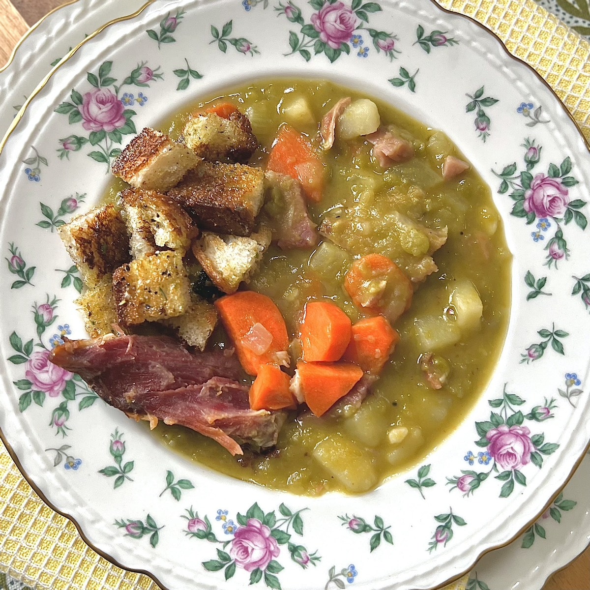 Split Pea and Ham Soup with Potatoes in decorative bowl topped with croutons.