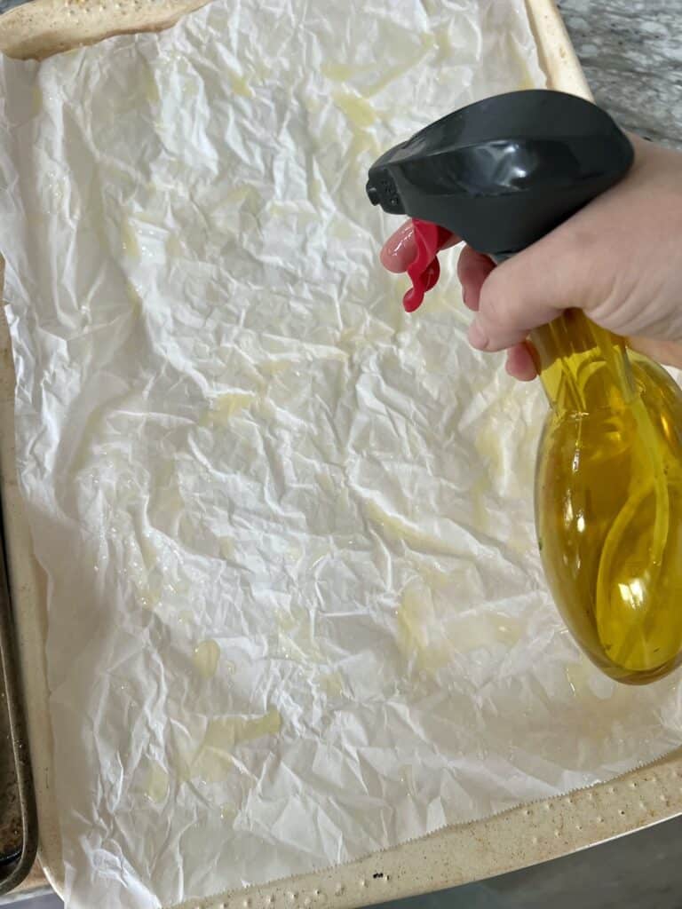 Spraying parchment paper with oil.