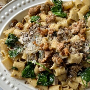 Norcina Pasta on white platter with grated parmesan in background.
