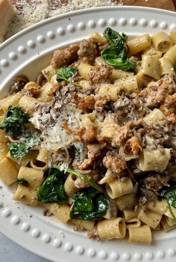Norcina Pasta on white platter with grated parmesan in background.