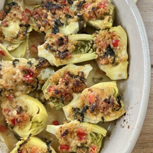 Finished, baked italian artichoke hearts oreganata in oval baking dish on yellow towel.