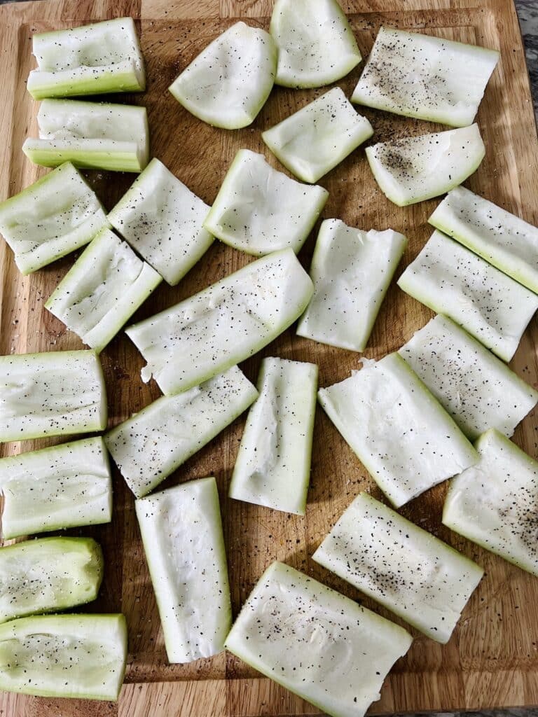Prepped and seasoned squash ready to be stuffed on a cutting board.
