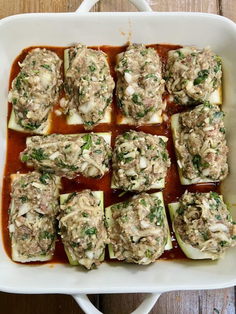 Stuffed cucuzza squash in white baking dish ready to bake.