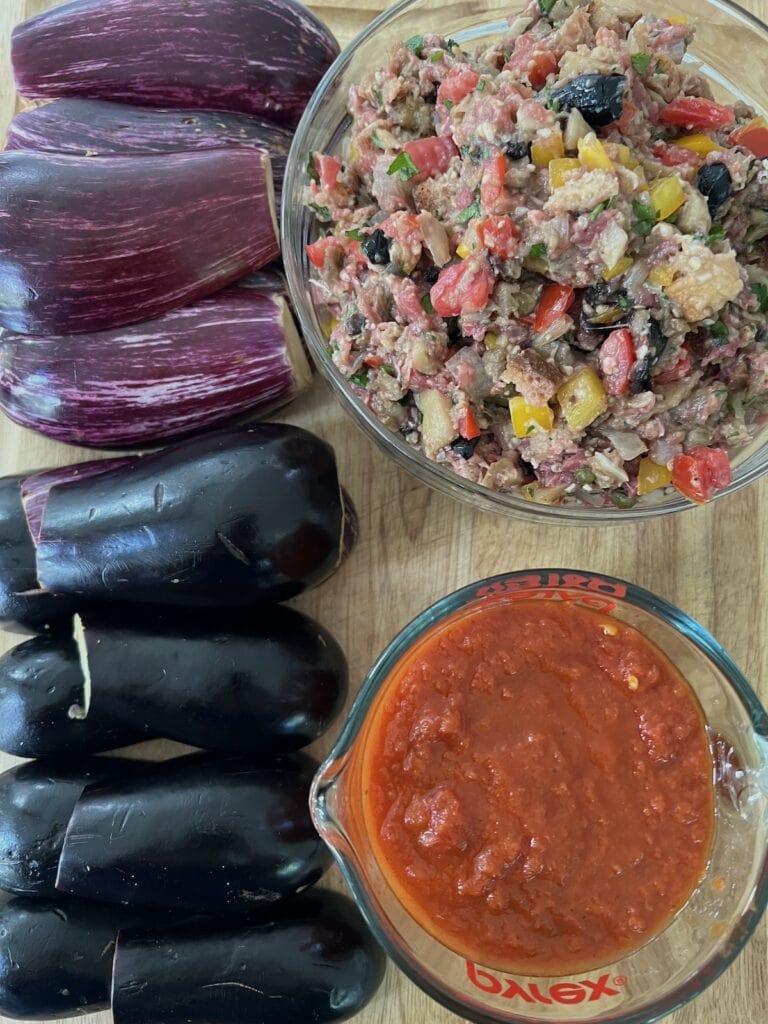 Halved and hollowed eggplant, tomato sauce and bowl of prepared eggplant filling ready to be assembled.