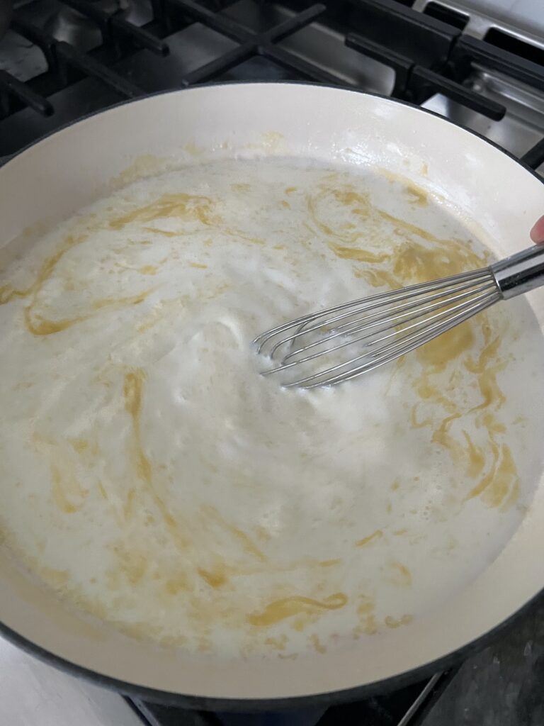 Whisking milk and roux together.