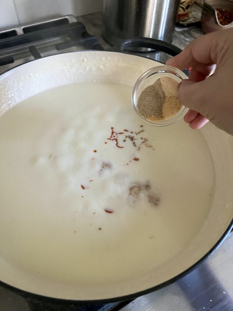 Adding seasonings to white sauce.