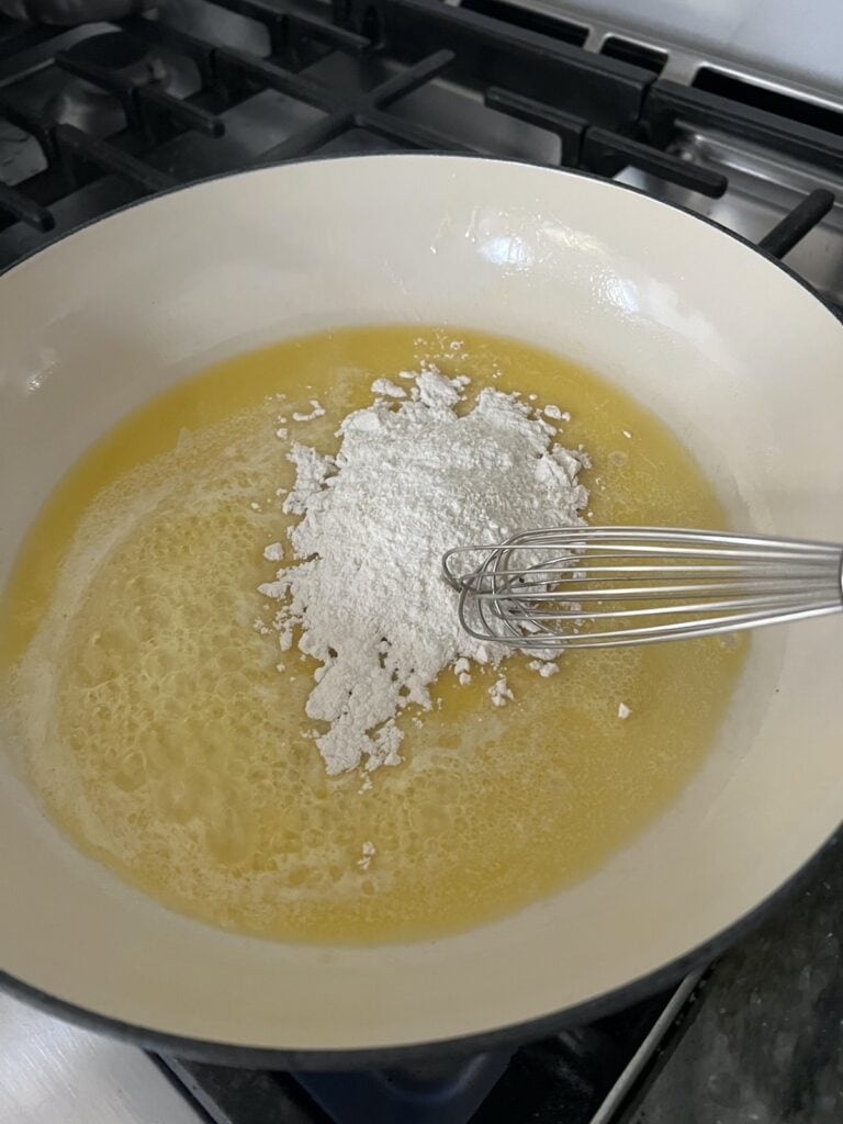 Making roux with melted butter and flour and whisk in large braiser pan.