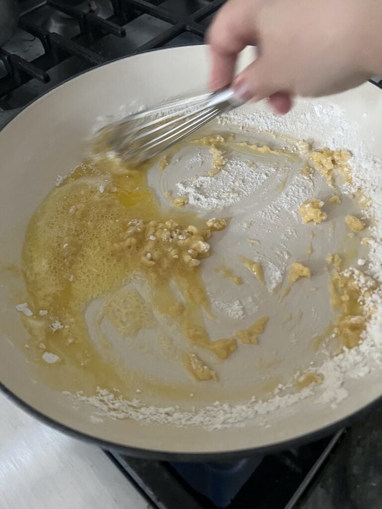 Whisking melted butter and flour together to make roux thickener.
