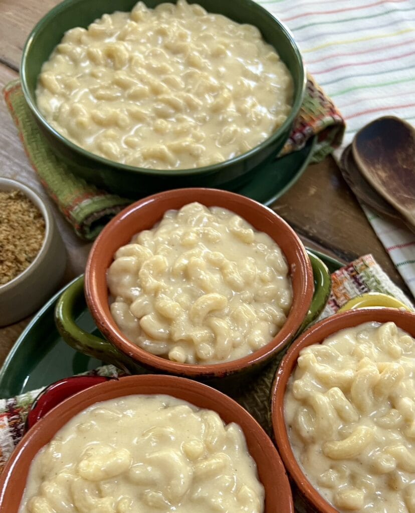 White Cheddar Cheese Mac and Cheese in four different colorful bowls over decorative towels.