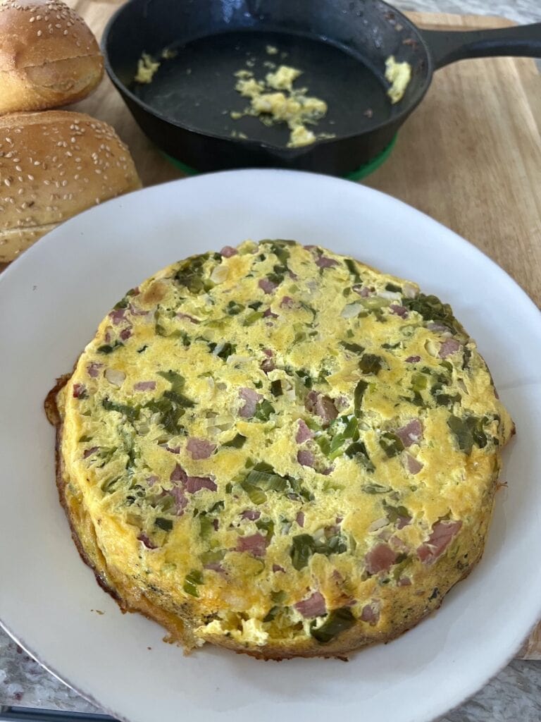 Ham and cheese frittata turned out from cast iron pan onto plate.